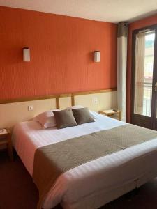 sypialnia z dużym łóżkiem i oknem w obiekcie Logis Hotel Restaurant des Voyageurs w mieście Le Malzieu-Ville