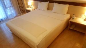 een slaapkamer met een groot wit bed en 2 nachtkastjes bij Atlas Cesme Apartments in Çeşme