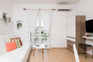 a living room with a white couch and a window at Aggelos Apartment in Limenas