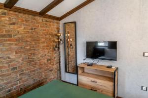 uma sala de estar com uma parede de tijolos e uma televisão em Hotel Hunters House em Ezerets