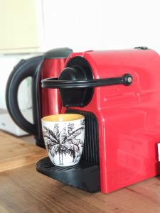 una caffettiera rossa con una tazza su un supporto di TERLA Bel Appartement 3 Pieces Clim & Parking a Saint-Pierre Altre 13 foto