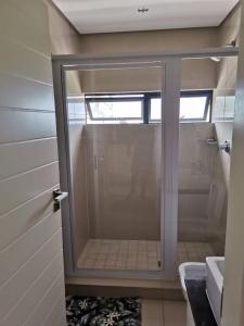 a glass shower door in a bathroom with a sink at Apartment 13 Santana Pebbles, 164 South Beach Road, La Mercy in La Mercy