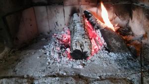 a log in a brick oven with a fire at Cabaña El Mirador de Bialet Masse in Villa Parque Siquiman