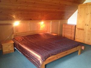 Bett in einem hölzernen Zimmer mit zwei Lichtern in der Unterkunft Gerti Haus in Bük