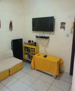 ein Wohnzimmer mit einem TV und einem gelben Tisch in der Unterkunft Apartabeach in Rio de Janeiro