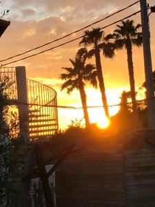 a sunset with palm trees in front of a building at Hôtel des Moulins in Allauch