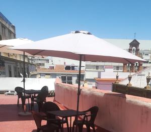 un patio con mesas, sillas y una sombrilla en Hostel Urban Sevilla, en Sevilla