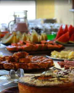 ein Tisch mit einer Reihe von verschiedenen Arten von Lebensmitteln in der Unterkunft Pousada Aliens in São Thomé das Letras