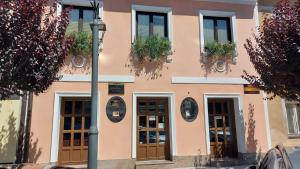 a pink building with doors and windows with potted plants at Apartma pri Gradu in Brežice