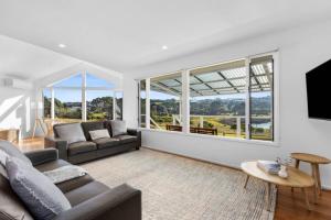 a living room with a couch and a table and windows at SALTWATER HOUSE - Opposite the beach and views over the lake! in Ocean Grove