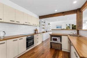 a large kitchen with white cabinets and wooden floors at SALTWATER HOUSE - Opposite the beach and views over the lake! in Ocean Grove