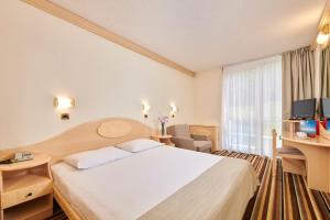 a hotel room with a bed and a desk at Hotel Istra Plava Laguna in Poreč
