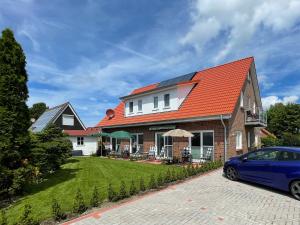 een huis met een oranje dak en een auto op de oprit bij Haus Nordseekrabbe in Greetsiel