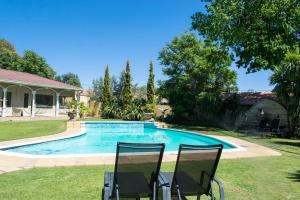 a pool with two chairs in a yard at Casa Romana B&B in Ladybrand
