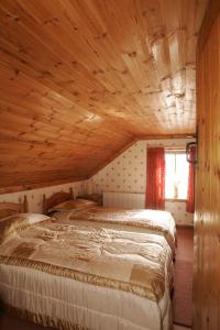 two beds in a room with wooden ceilings at Cummins Cottages in Ballycrossaun