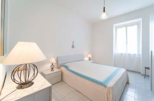 una camera bianca con letto e lampada di Onda Blu ad Alghero
