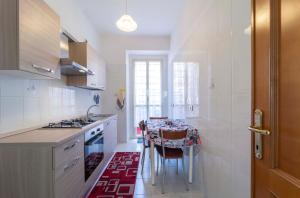 una cucina con tavolo e una cucina con elettrodomestici bianchi di Onda Blu ad Alghero