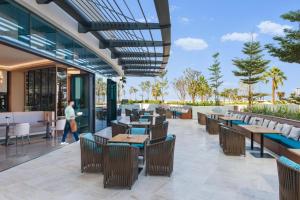 a restaurant with tables and chairs and a person walking by at Beach Resort Residences - Platinium Dubai in Dubai