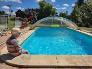 a little boy sitting next to a swimming pool at Apartmány Roudnice in Jestrabi V Krkonosich