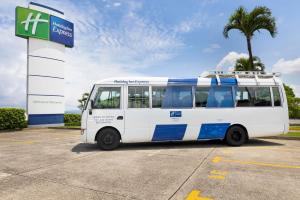 a white and blue bus parked at a gas station at Holiday Inn Express San Jose Costa Rica Airport by IHG in Alajuela City