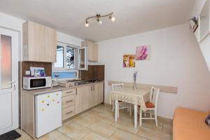 uma cozinha com uma mesa e um frigorífico branco em Apartments Lovro em Dubrovnik