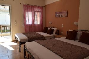 a hotel room with two beds and a window at Lafazanis rooms in Nea Vrasna