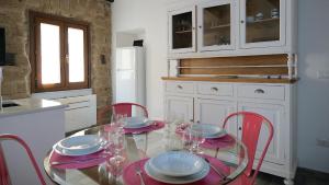 a kitchen with a glass table and red chairs at Welcomely - Santa Chiara in Alghero