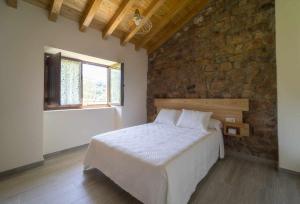 a bedroom with a bed and a stone wall at Complejo Rural El Cerradón in Alceda