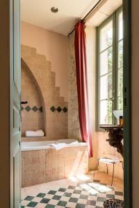 een badkamer met een bad en een raam bij Hôtel Mas Vidau Porte des Alpilles in Saint-Étienne-du-Grès