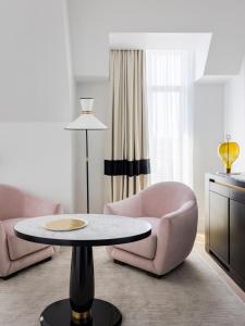 un salon avec une chaise rose et une table dans l'établissement Kimpton - St Honoré Paris, an IHG Hotel, à Paris