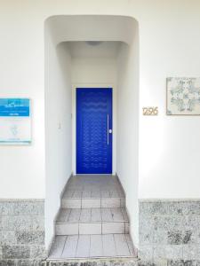 a blue door in a white wall with a staircase at B&B Stella Marina in Capo dʼOrlando