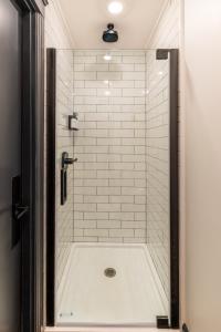a bathroom with a shower with a white tile shower at The Dorm Hotel in Ithaca