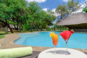 two cocktails on a table next to a swimming pool at Mongena Private Game Lodge in Rust de Winter