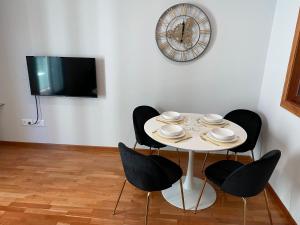 a white table with chairs and a clock on a wall at Maison San Isidoro - GARAJE y WIFI GRATUITO in León
