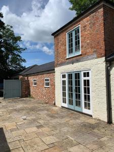 un edificio de ladrillo con puertas blancas y un patio en Coach House, Minting. en Horncastle