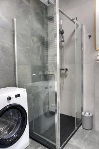 a washing machine in a bathroom with a glass shower at Essence Apartments Topaz in Poznań