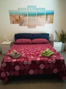 een slaapkamer met een roze bed en 2 handdoeken bij "Villetta tra Mare e Barocco" in Marina di Ragusa