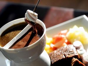 eine Tasse Kaffee mit einem Löffel neben einem Teller Essen in der Unterkunft Rusland Pool Hotel in Bouth