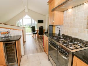 a kitchen with a stove and a dining room at 2 Cae Mattw in Abergele
