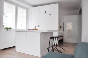 eine Küche mit weißen Schränken, einer Spüle und einem Hocker in der Unterkunft Studio Emmi in Ljubljana