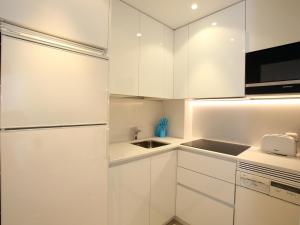 una cocina blanca con armarios blancos y fregadero en Orly, en San Sebastián
