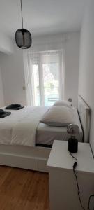 a white bedroom with a bed and a window at Barakokula in Omiš