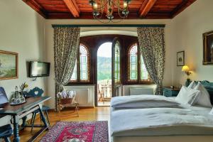 a bedroom with a bed and a desk and windows at Hotel See-Villa in Millstatt