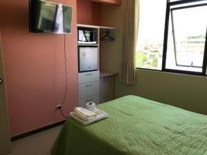 a bedroom with a bed with a tv on the wall at Rooms MD y FS in Huancayo