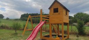 a wooden playground with a slide and a house at Apartmány Kraš in Velká Kraš