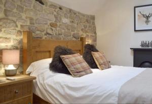 a bedroom with a white bed with a stone wall at Little Cottage in Cromford