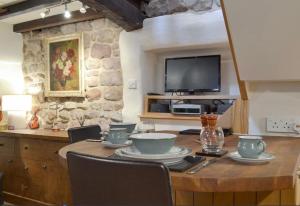 a dining room with a table and a tv at Little Cottage in Cromford