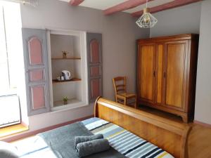 1 dormitorio con 1 cama, armario y silla en Le Logis de Lou, en Blars