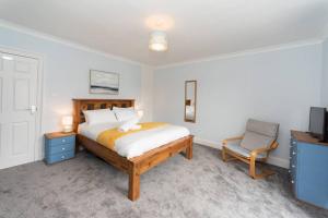 a bedroom with a bed and a chair and a television at Large House in Looe, Near Beach and Bars with Great Views, Free Parking and Free Access to a Nearby Indoor Swimming Pool in Looe