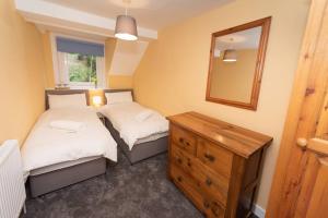 a room with two beds and a mirror and a dresser at Large House in Looe, Near Beach and Bars with Great Views, Free Parking and Free Access to a Nearby Indoor Swimming Pool in Looe